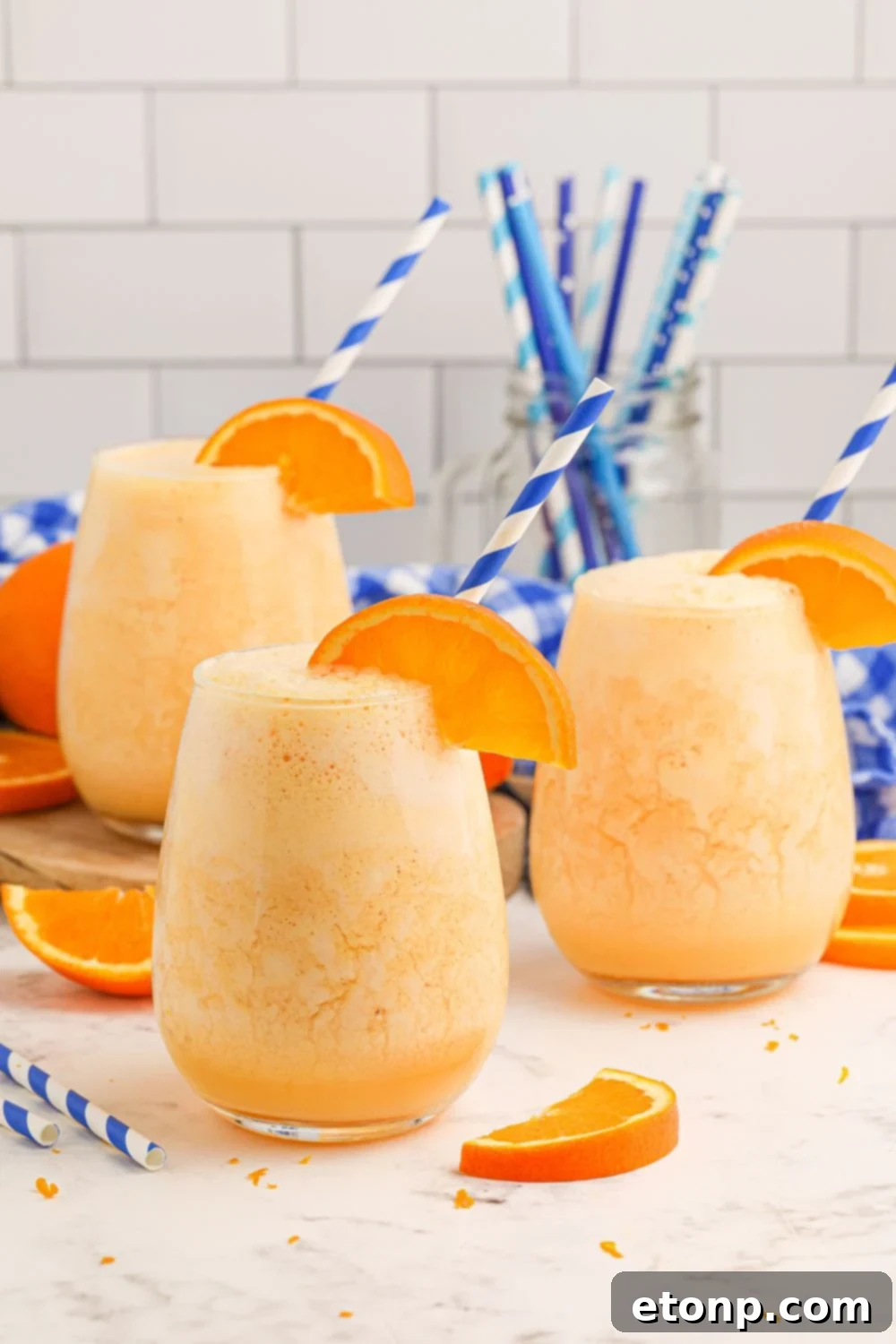 Copycat Orange Julius drinks on table with a container of straws in the background 