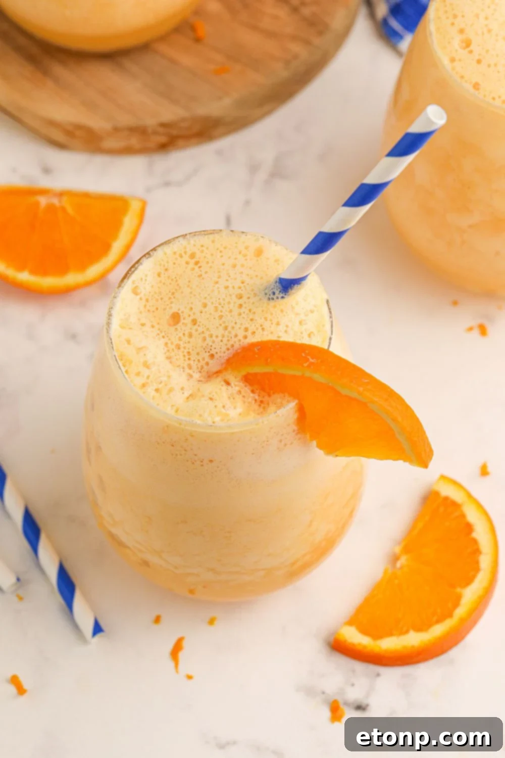 Copycat Orange Julius overhead shot of a glass with staw and orange in glass with orange slices on table 