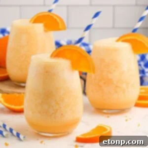 Copycat Orange Julius in three glasses on table with an orange slice on rim and straw in each glass
