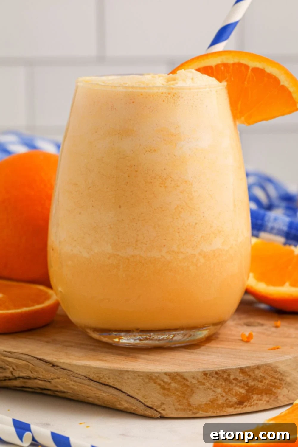 Copycat Orange Julius in a small glass on table with a blue straw in it 