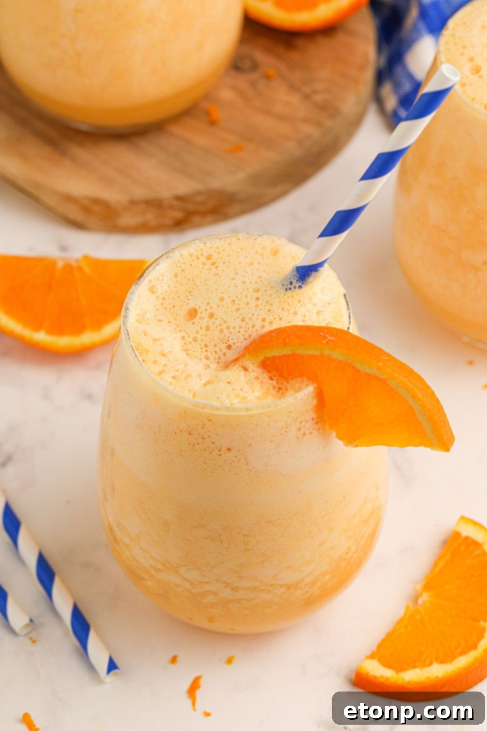 Copycat Orange Julius drinks on table with straws and orange slices scattered on table 