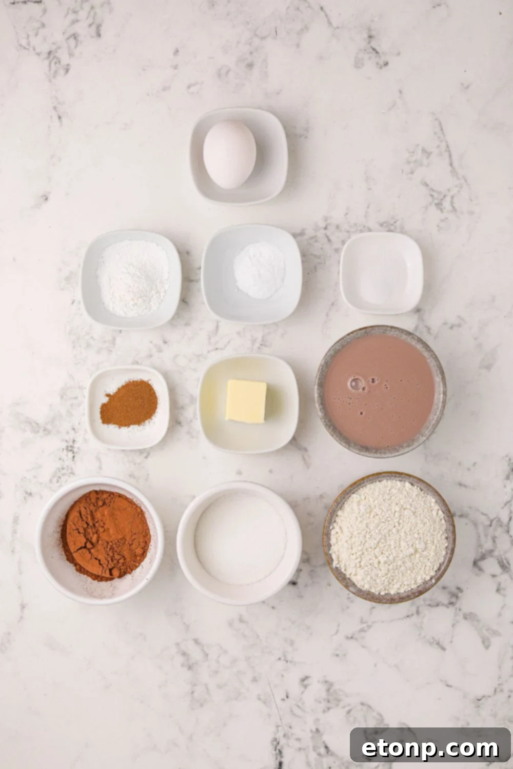 A collection of fresh ingredients laid out on a rustic wooden table, including flour, cocoa powder, sugar, eggs, and milk, all essential for making delectable hot chocolate pancakes.