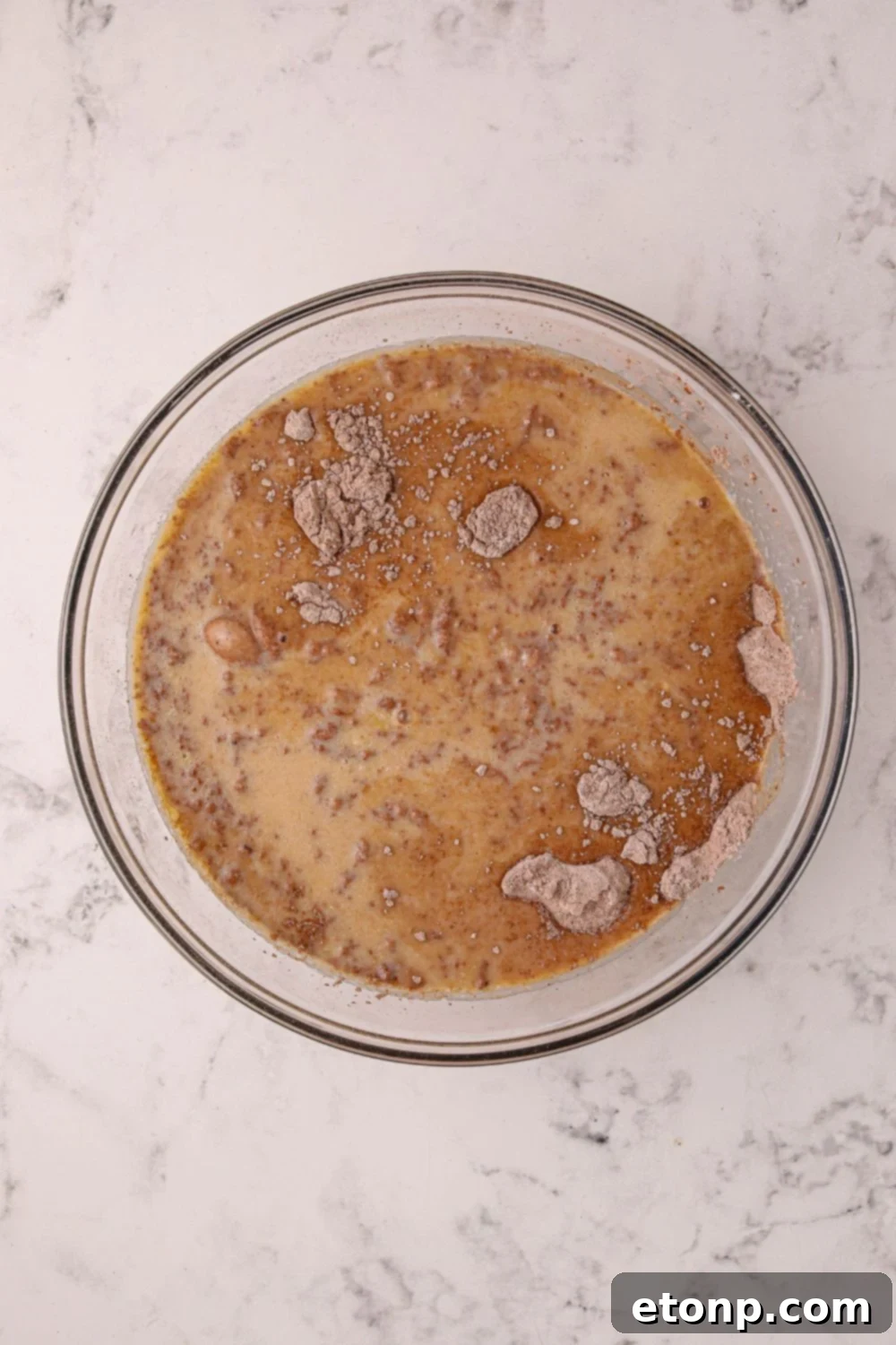 Various ingredients for Hot Chocolate Pancakes, including both wet and dry components, carefully combined in a large mixing bowl on a kitchen table.