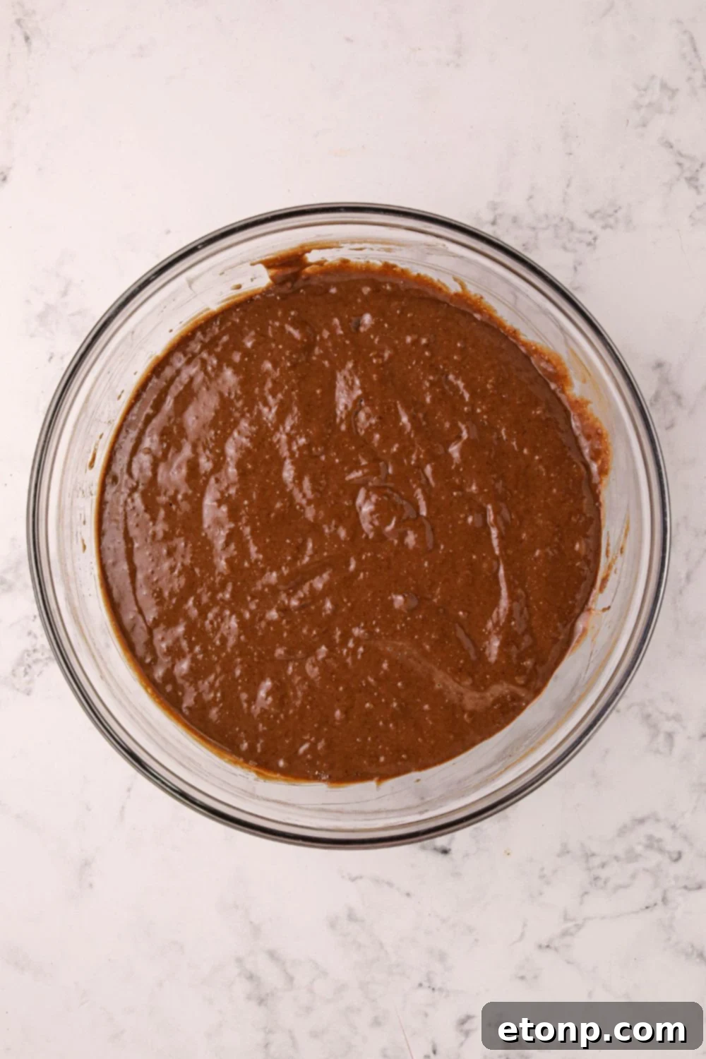 Smooth, rich Hot Chocolate Pancake batter resting in a clear glass bowl, showcasing its readiness for cooking.
