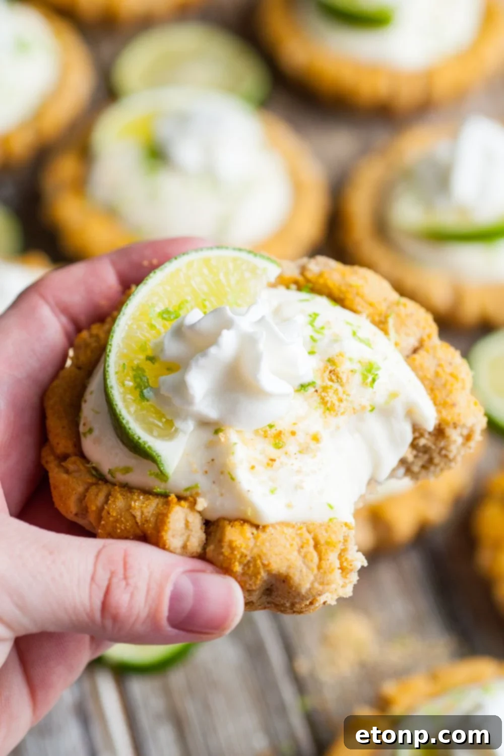 Crumbl Key Lime Pie Cookie being held in hand with a small bite taken out of the cookie