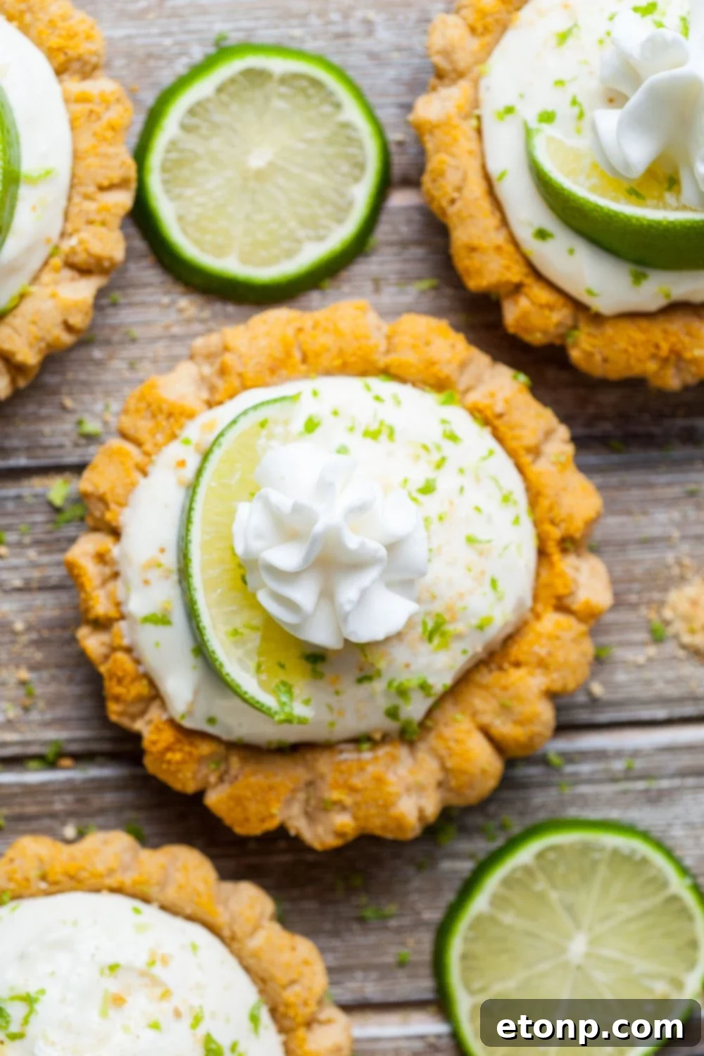 Crumbl Key Lime Pie Cookies spread out on a wooden table with lime slices around the cookies