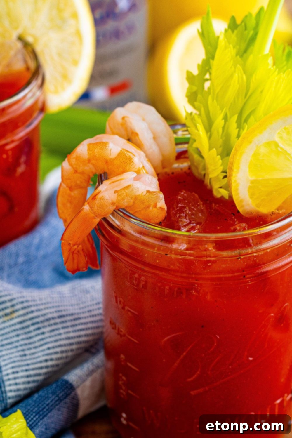 A close-up shot of a Bloody Mary cocktail in a glass, featuring a large, succulent shrimp and a crisp celery stalk as garnishes, highlighting the drink's savory appeal.