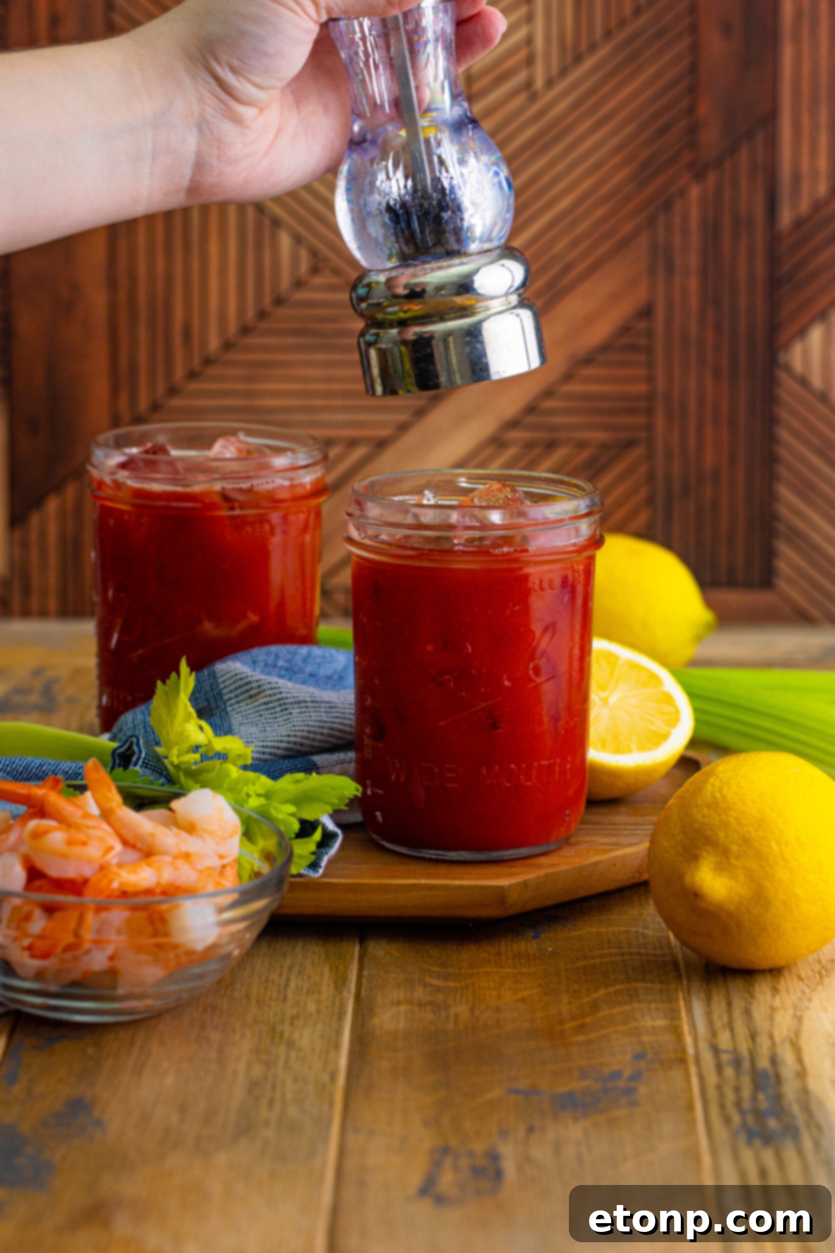 Finishing a Bloody Mary with a sprinkle of freshly cracked black pepper, adding an aromatic touch to the drink.