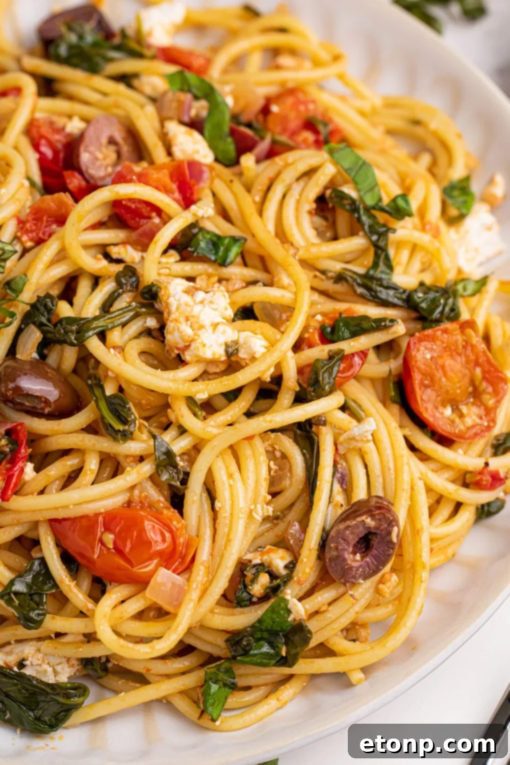 Greek Spaghetti on a plate, offering a tempting side view that showcases the bountiful mix of ingredients