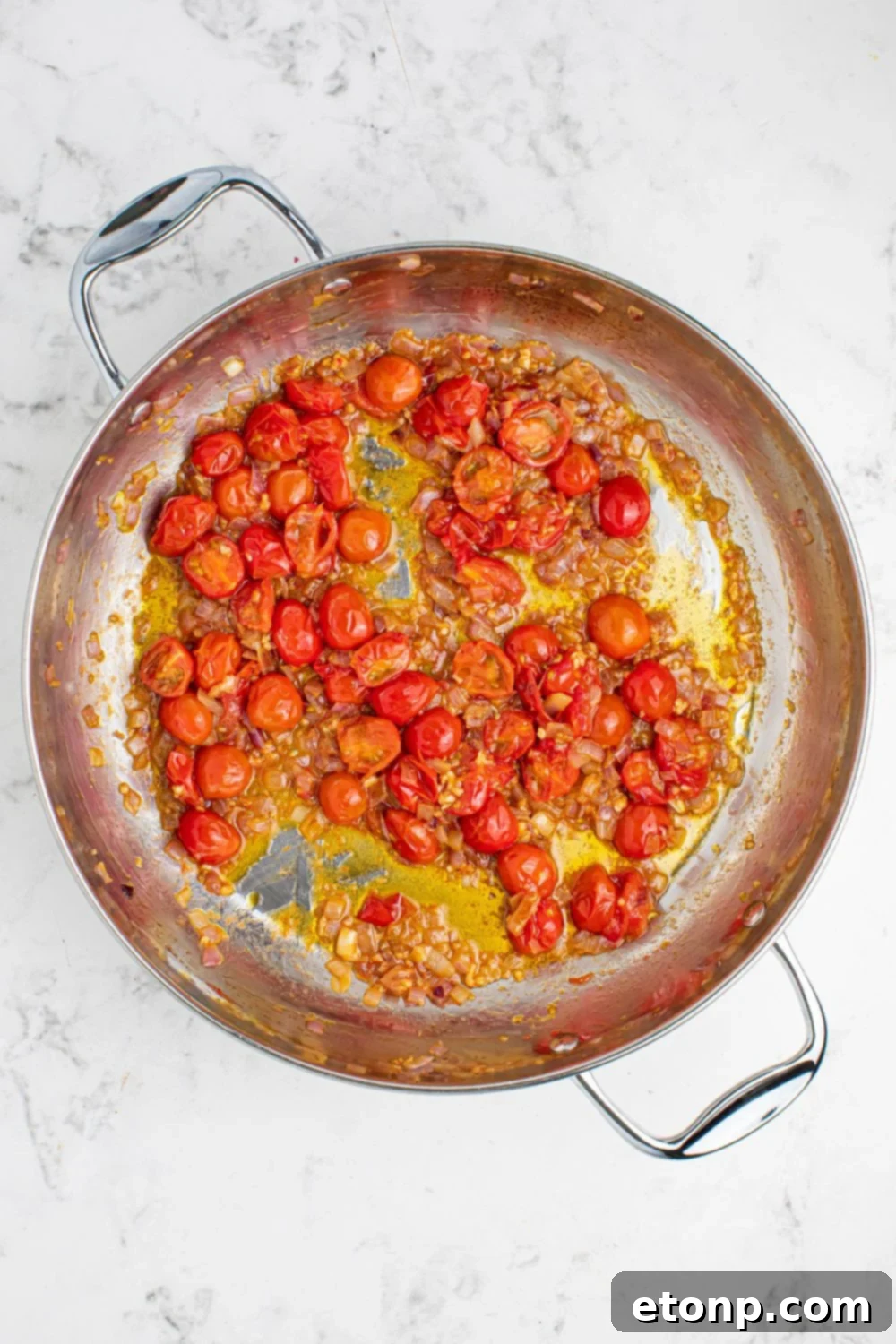 Cherry tomatoes roasting in a pan with a drizzle of olive oil, ready to be incorporated into the Greek Spaghetti