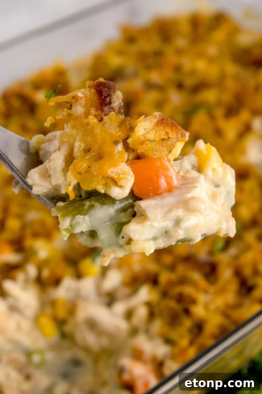 Chicken Stuffing Casserole in pan with a metal pan scooping out the mixture 