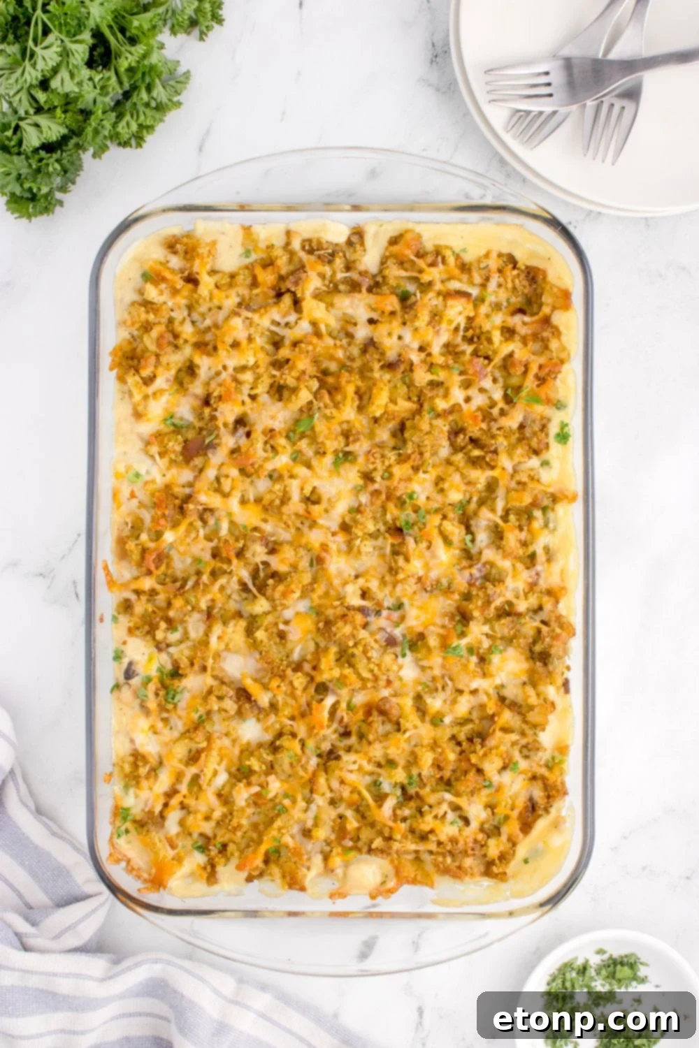 Chicken Stuffing Casserole on table in a glass casserole dish with fresh parsely around the pan on table
