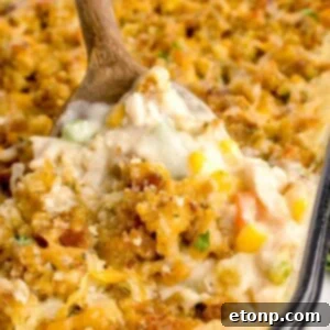 Chicken Stuffing Casserole in a pan with a wooden spoon scooping some of the casserole out of the pan