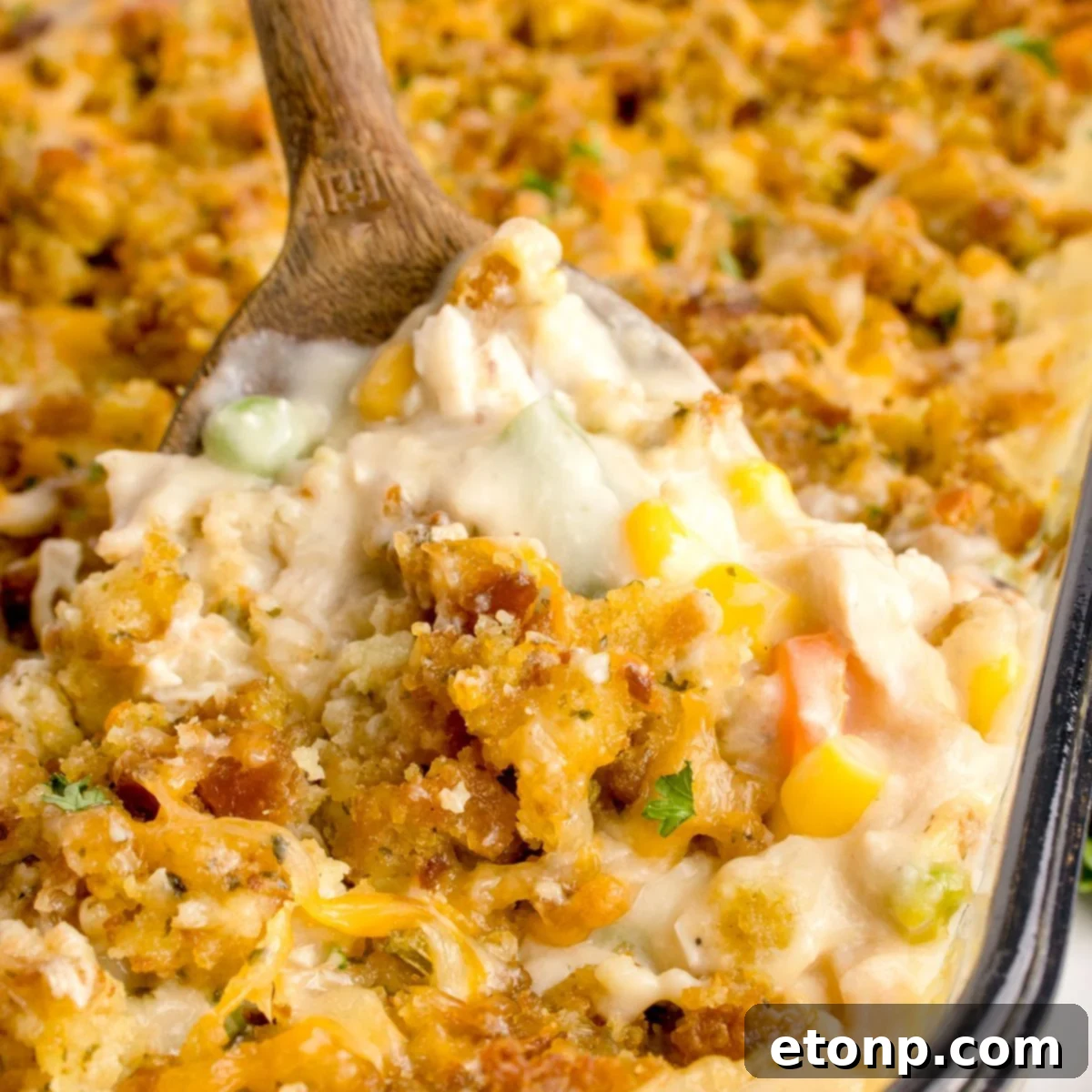 Chicken Stuffing Casserole in a pan with a wooden spoon scooping some of the casserole out of the pan
