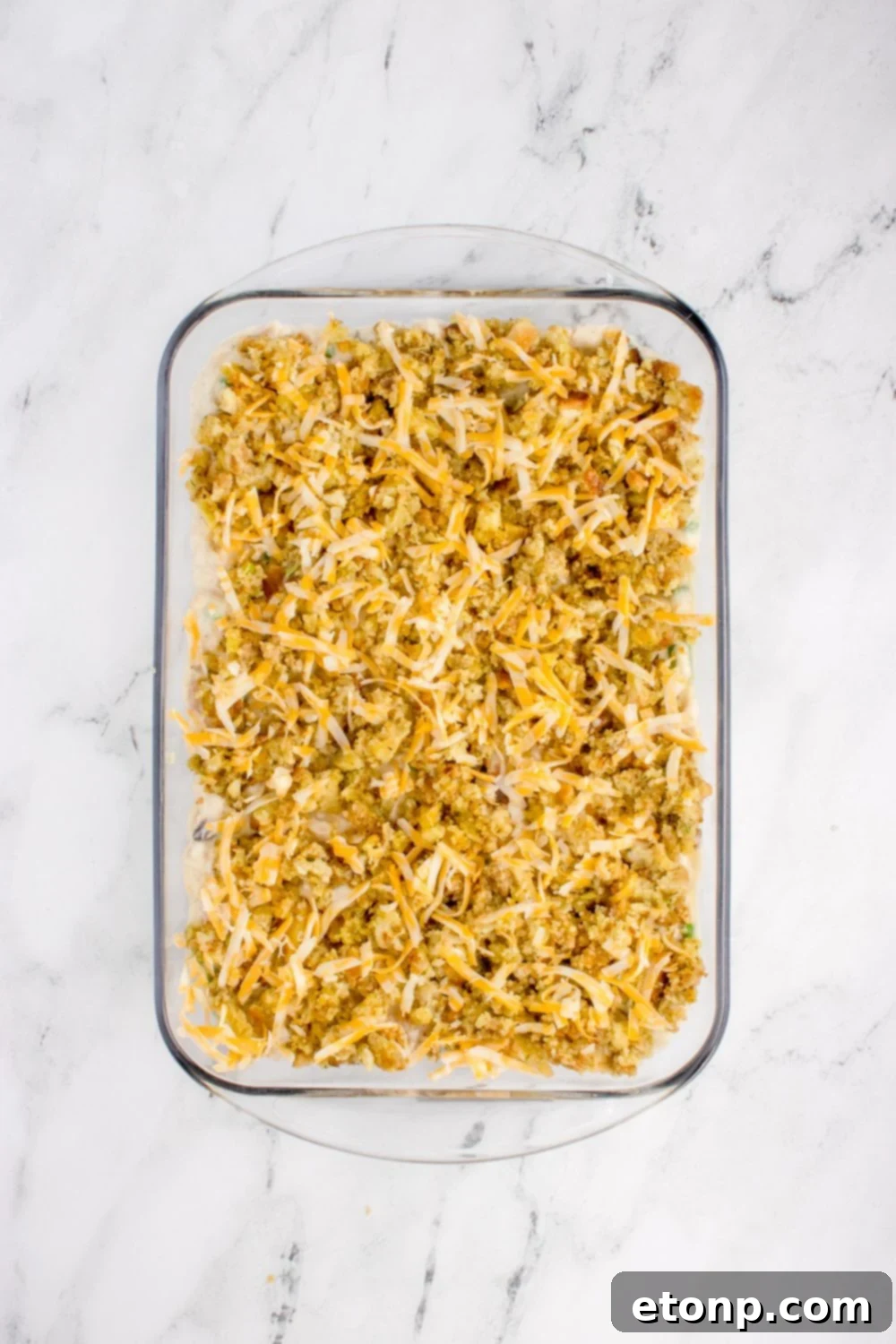 Chicken Stuffing Casserole overhead look with cheese on top of stuffin mix in the casserole pan 