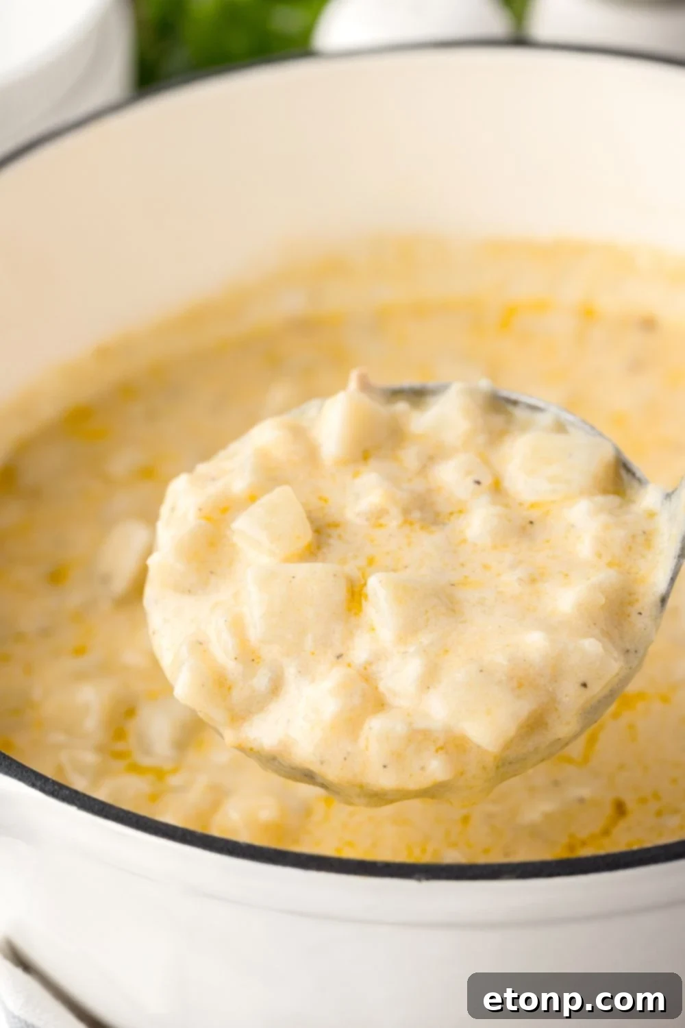 Hash Brown Potato Soup in a ladle above a pot of soup 