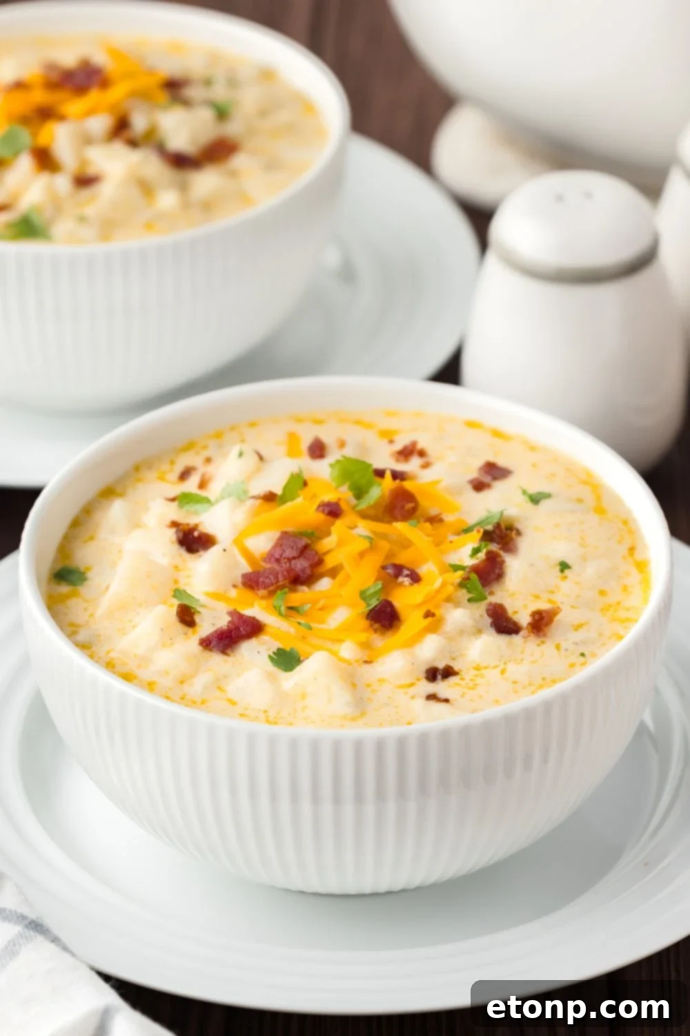 Hash Brown Potato Soup in bowls on table with salt and pepper on side 