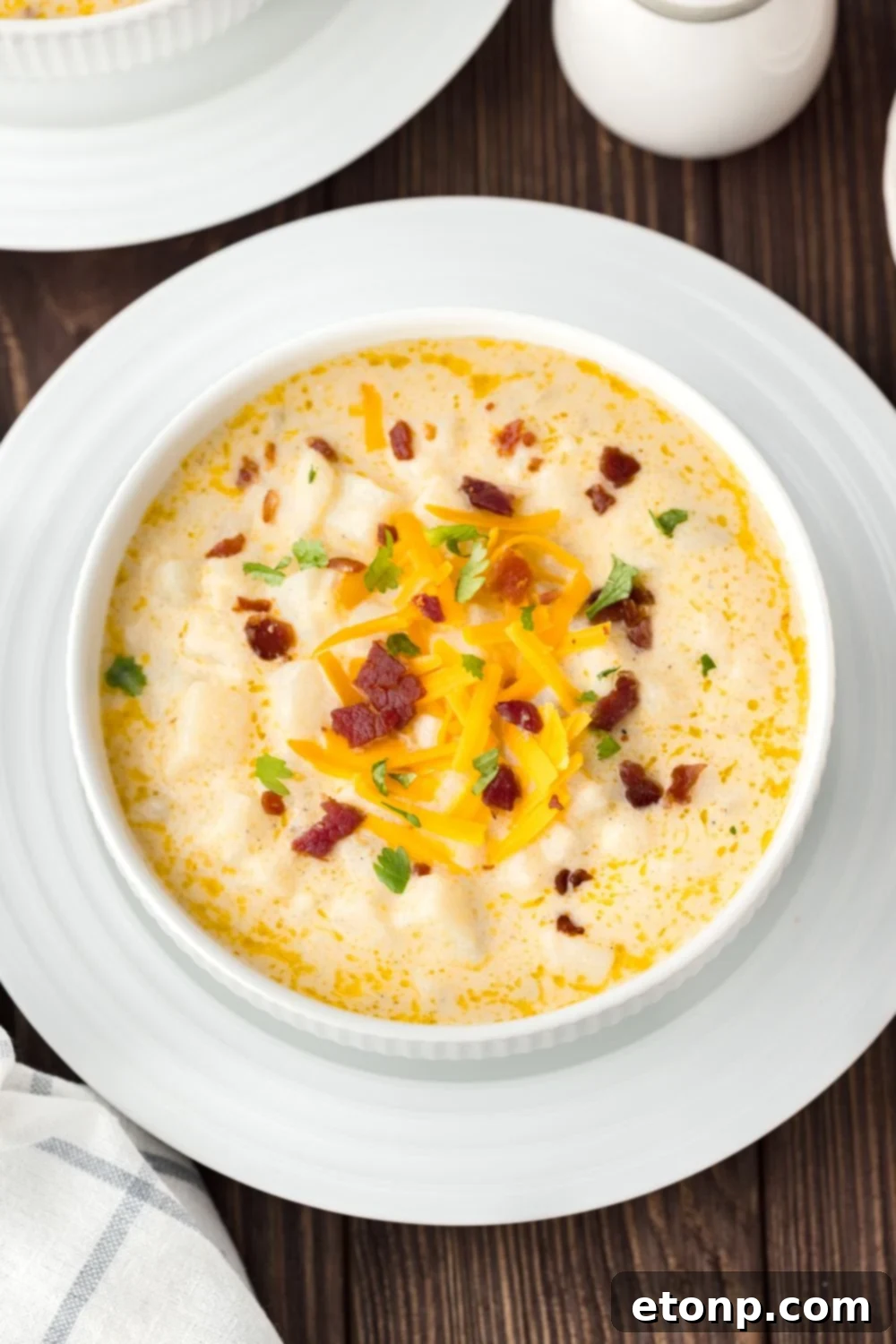 Hash Brown Potato Soup in a bowl with a plate under it 