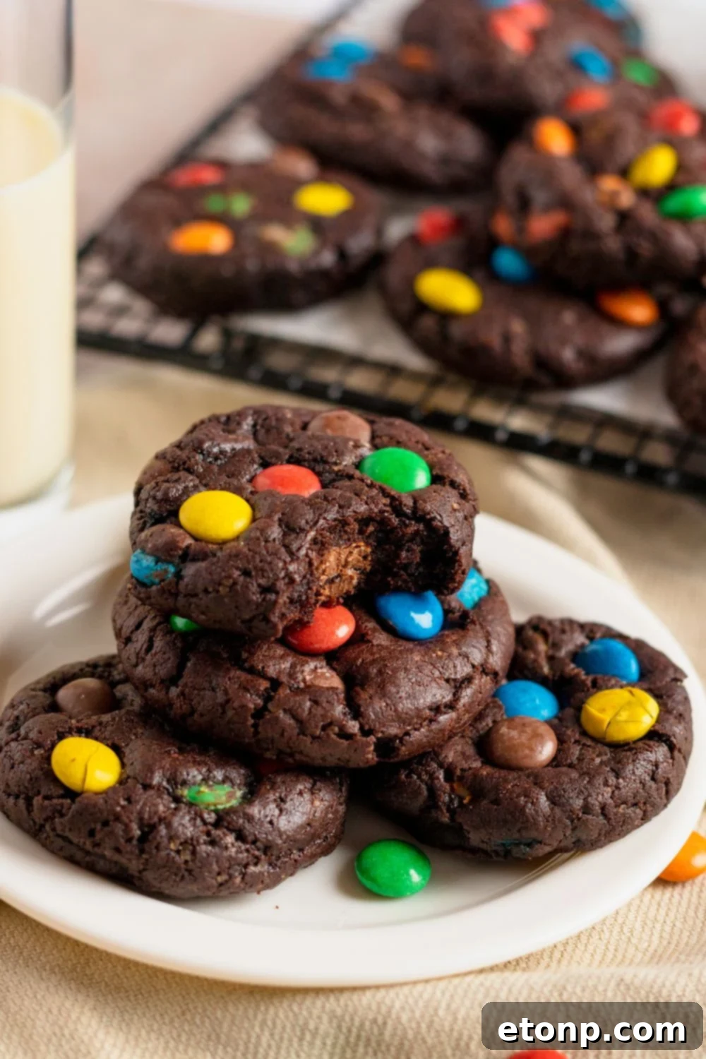 Chocolate M&M Cookies on a plate with one cookie with a bite taken out of it 