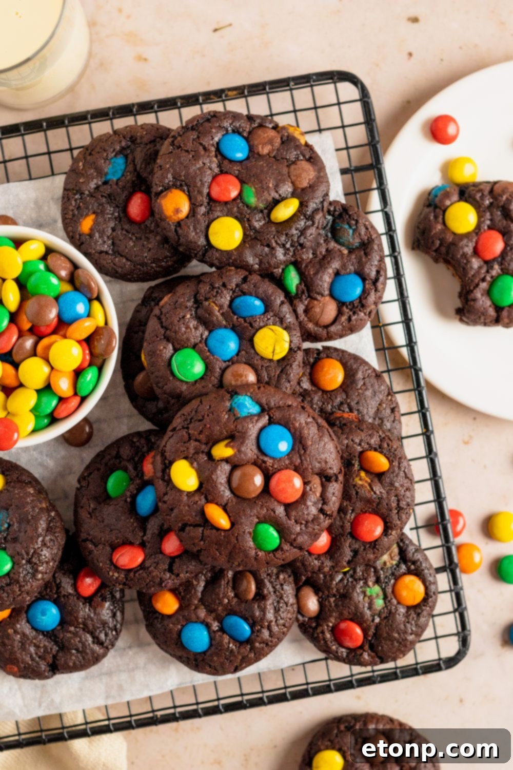 Chocolate M&M Cookies on a coolig rack with a bowl of M&Ms to the side of tray 