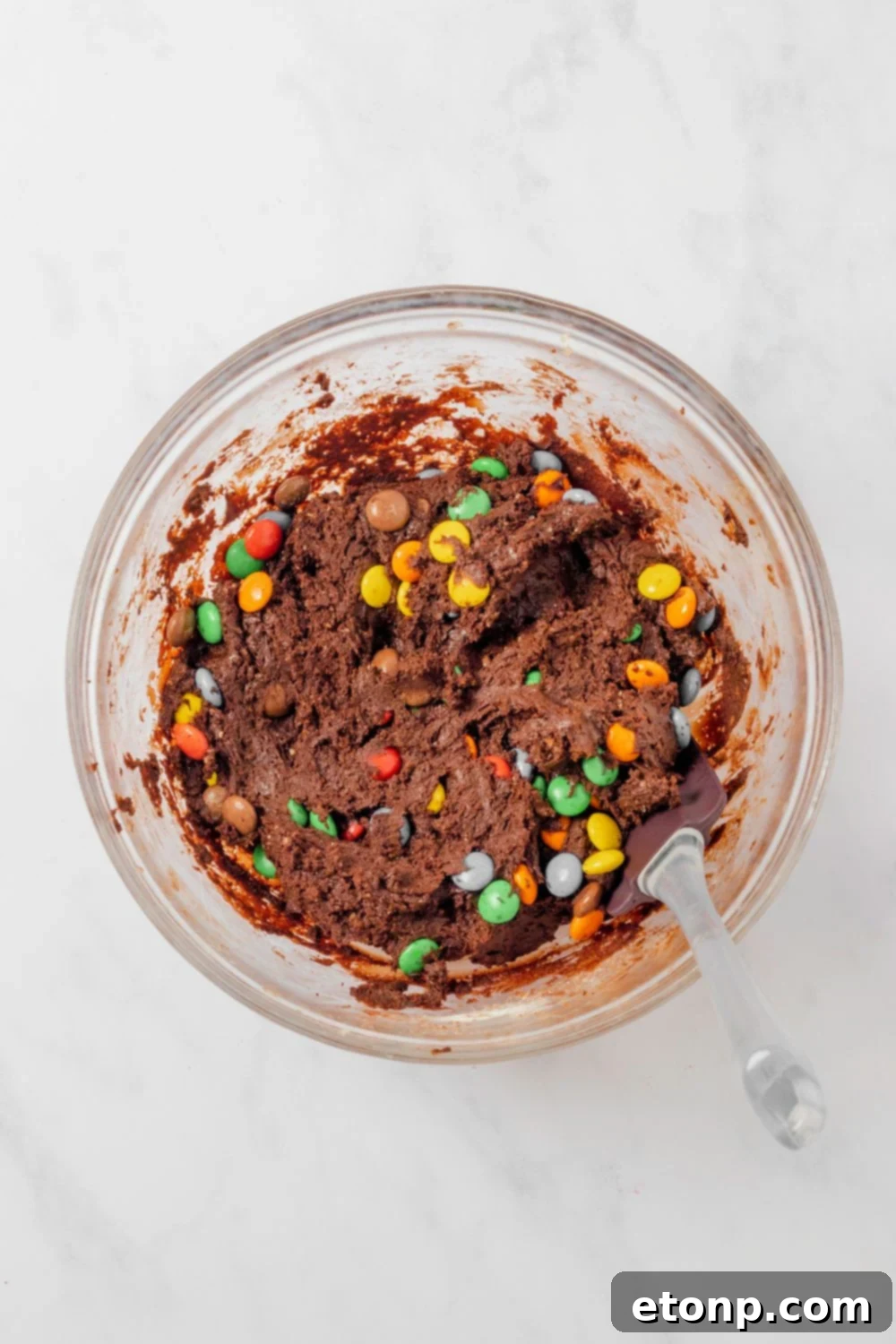 Chocolate M&M Cookies raw batter in a glass bowl with a fork in it 