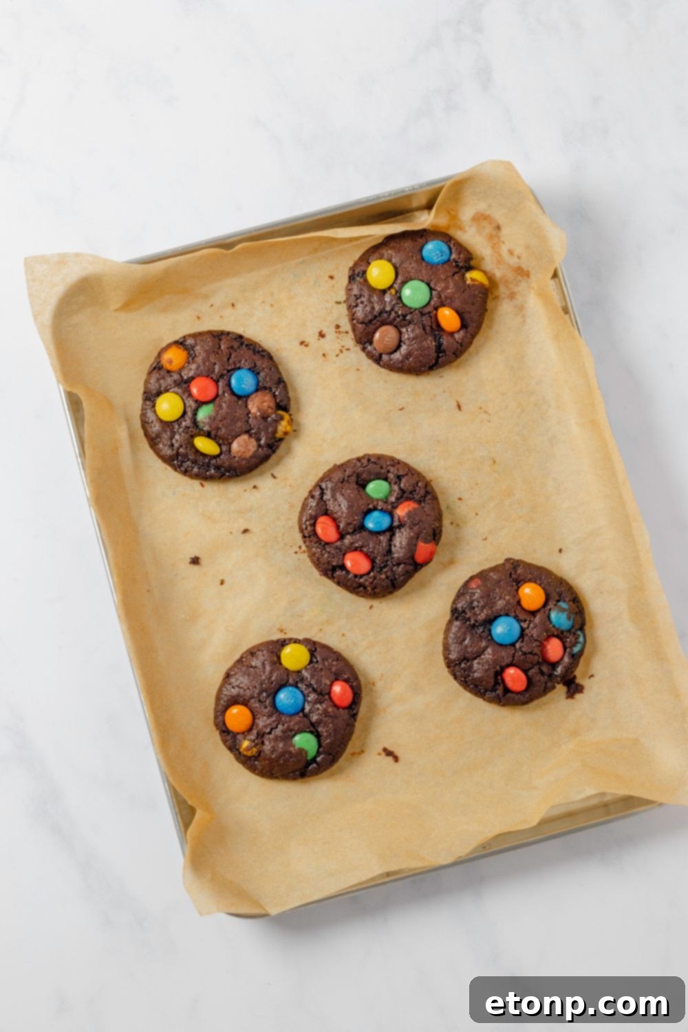 Chocolate M&M Cookies baked on a cookie sheet sitting on table