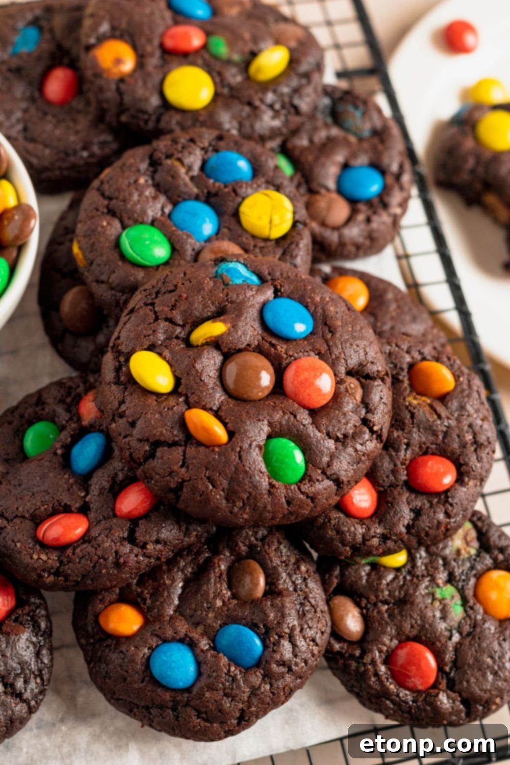 Chocolate M&M Cookies on a table all stacked on top of each other 