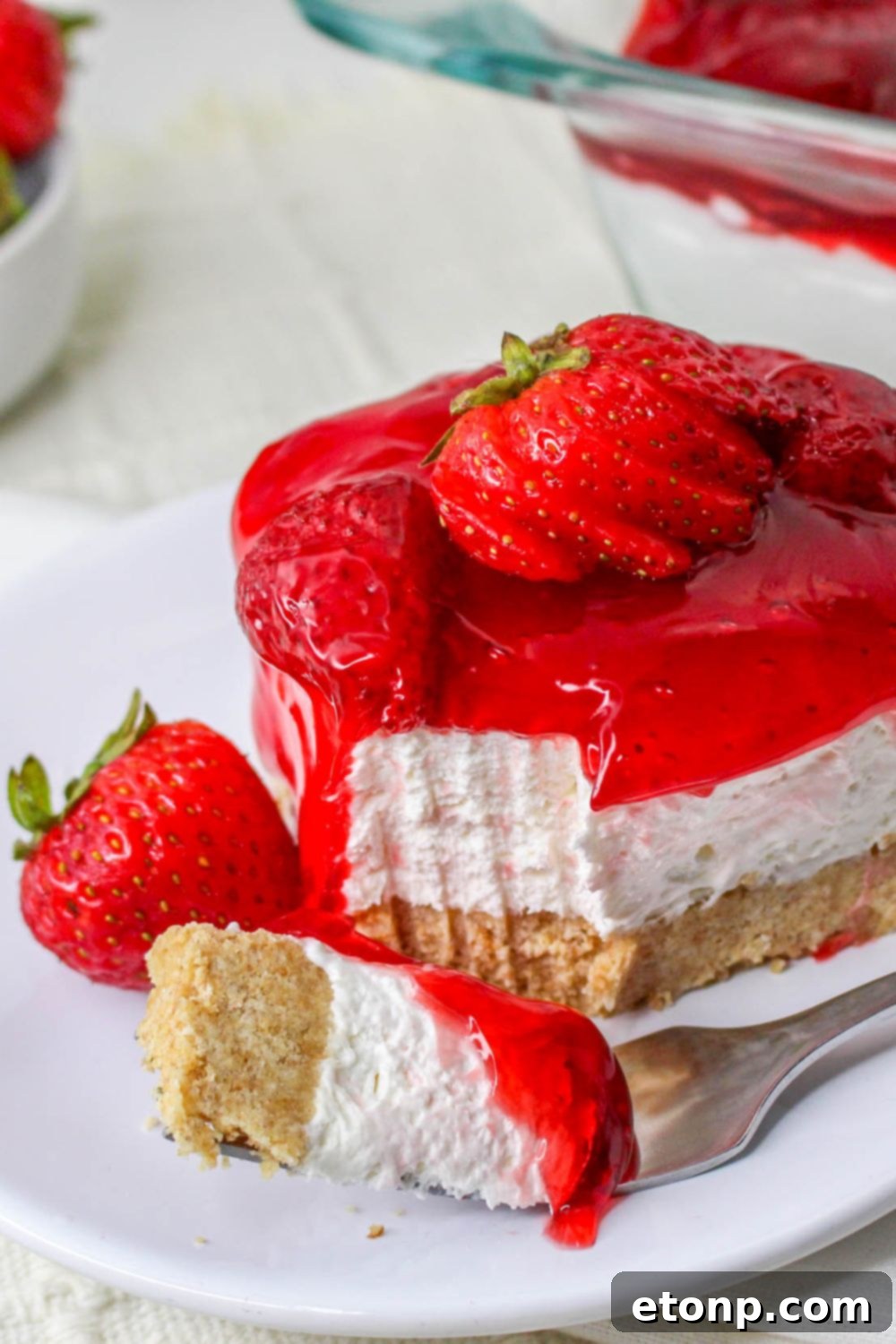 No Bake Strawberry Delight on plate with a fork with a bite on it and berry on plate 