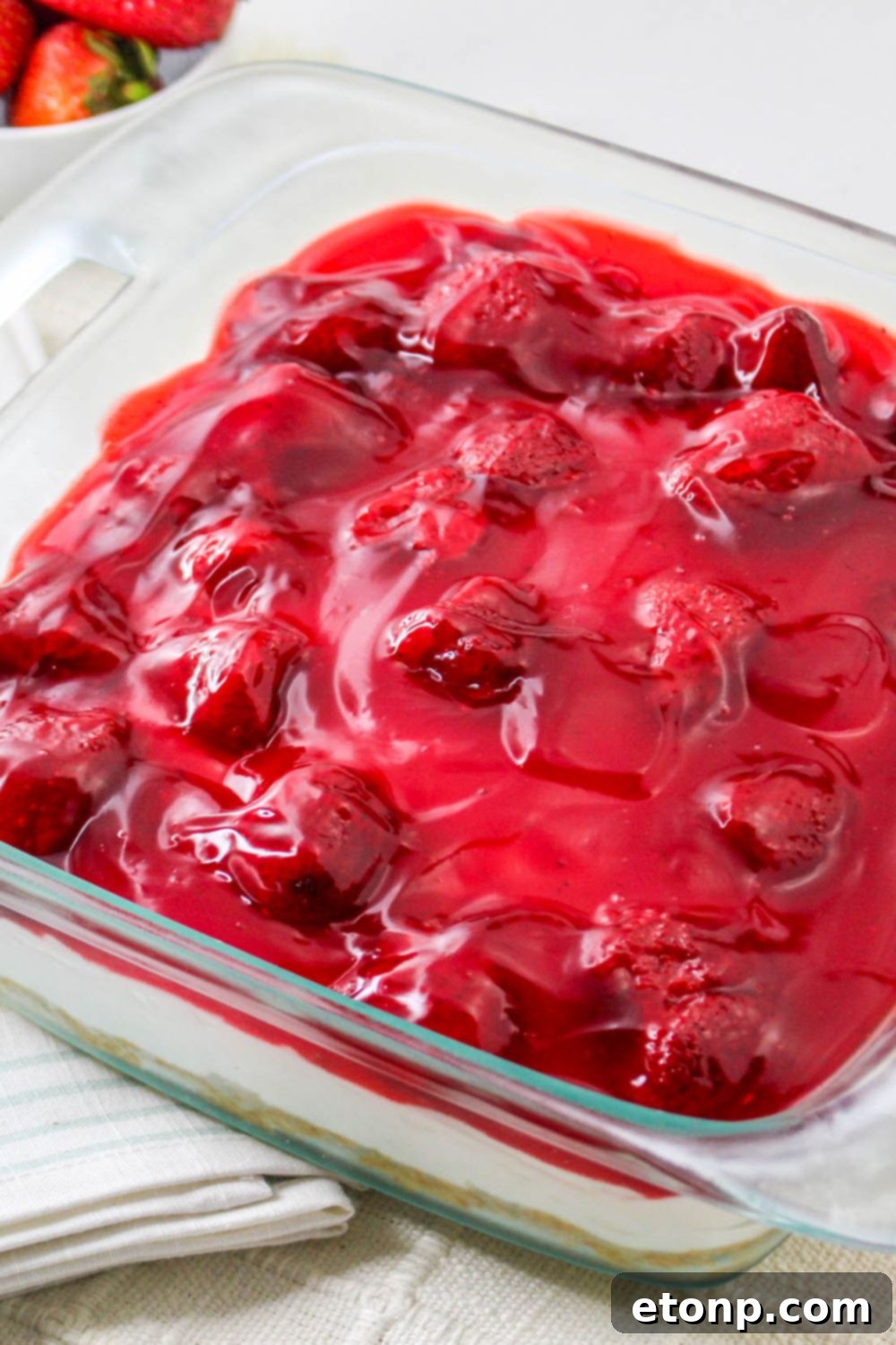 side view of No Bake Strawberry Delight in a glass pan on table 