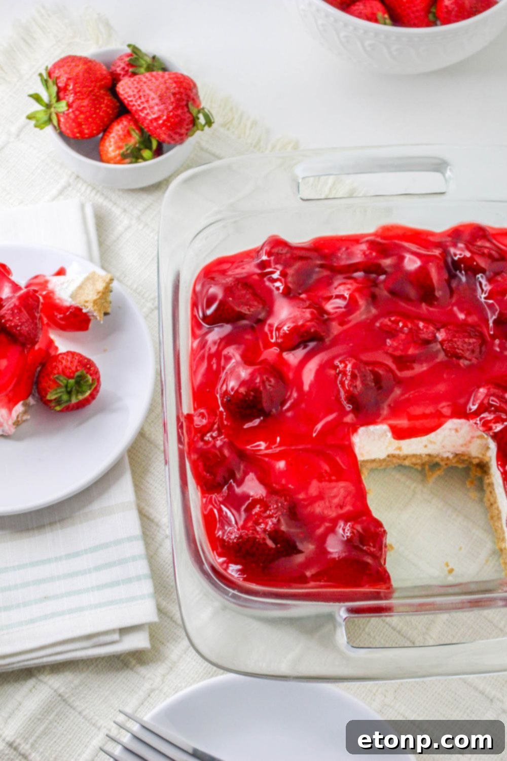No Bake Strawberry Delight in a glass pan with a slice taken out of it 