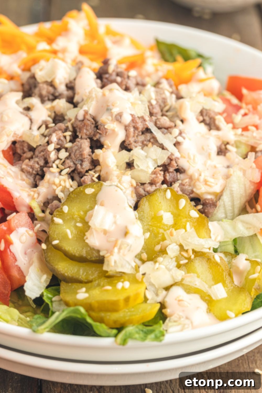A close-up view of the Big Mac Salad in a bowl, clearly showing the appetizing layers of ground beef, shredded cheese, and chopped vegetables, all generously coated with the signature dressing.