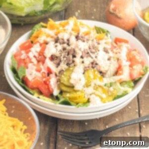 Big Mac Salad in a bowl on table with ingredients around bowl on table