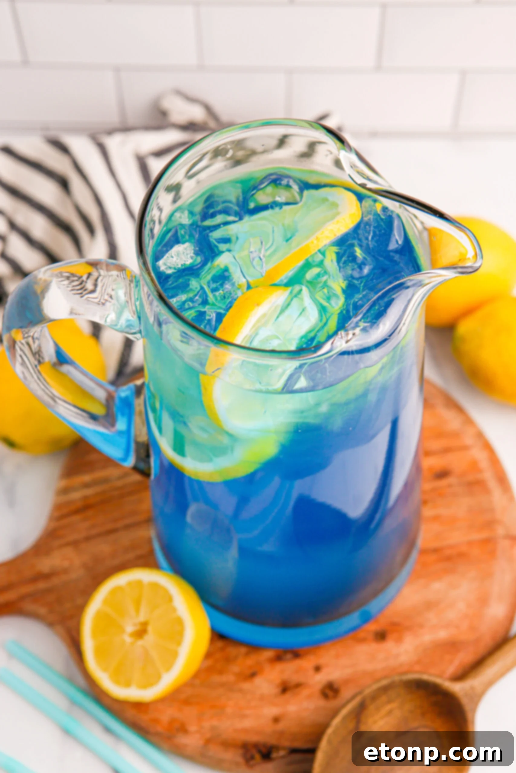 Blue Raspberry Lemonade in a pitcher with sliced lemons inside, ready to be served on a hot day.