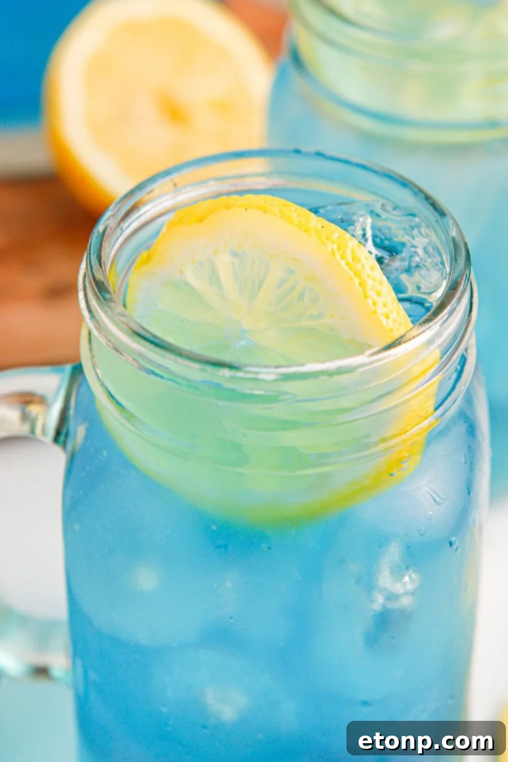 A close-up shot of Blue Raspberry Lemonade in a glass, elegantly garnished with a lemon wheel on top.