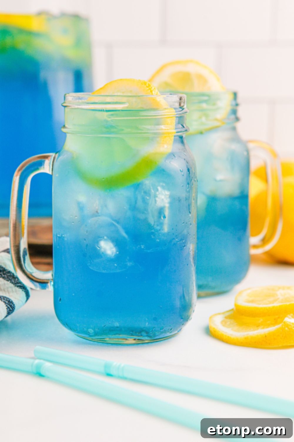 Homemade Blue Raspberry Lemonade served in mason jars, garnished with fresh lemon wedges.