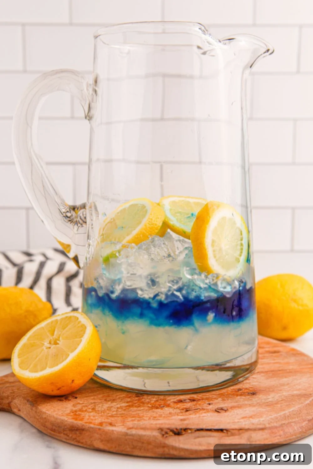 Blue raspberry syrup being poured into a glass pitcher, adding vibrant color to the lemonade base.