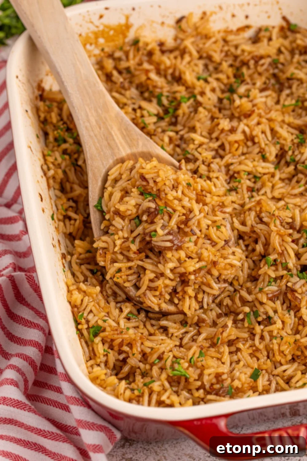 A wooden spoon with a portion of Stick of Butter Rice resting in the pan, showcasing its perfect texture.