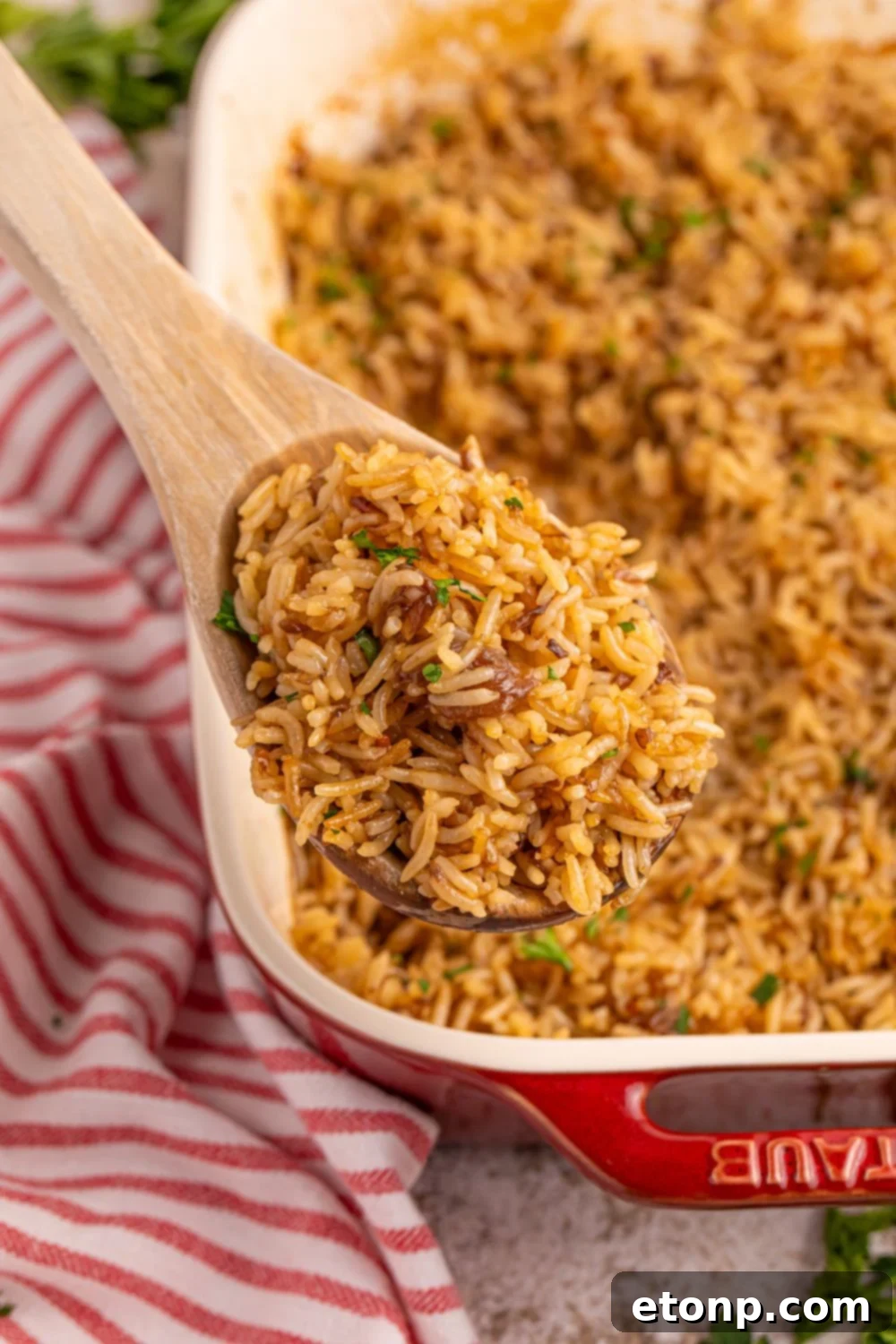 A casserole dish of Stick of Butter Rice with a spoon scooping a generous portion.