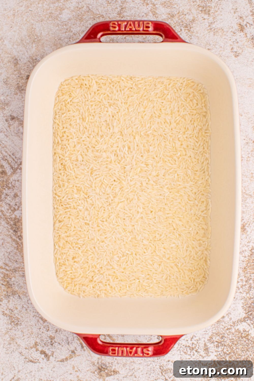 Plain long-grain rice ready in a casserole dish before adding other ingredients for Stick of Butter Rice.