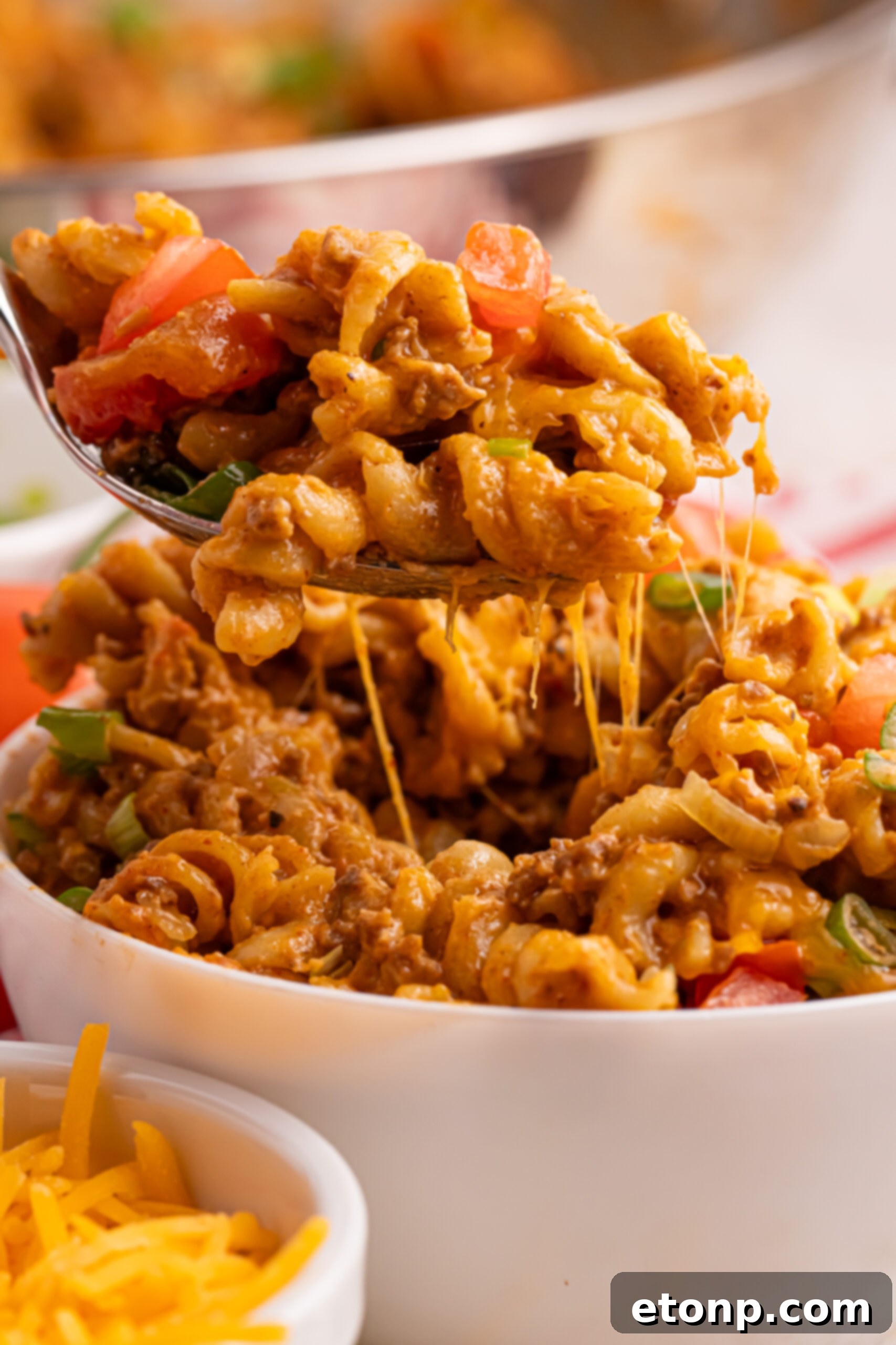 Taco Macaroni and Cheese in a white bowl with a fork lifting up a bite