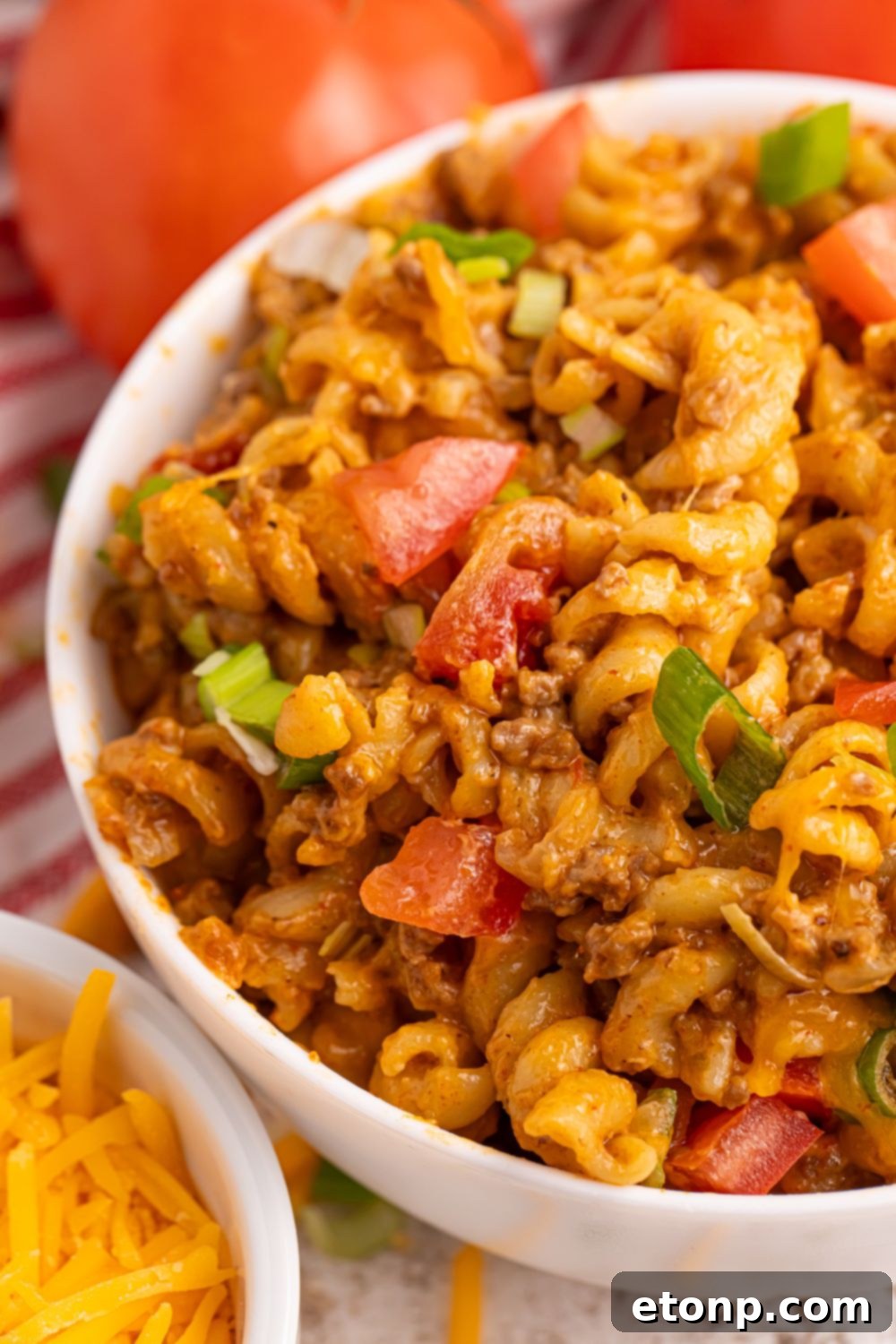 Taco Macaroni and Cheese in a bowl with tomatoes and green onions on top 