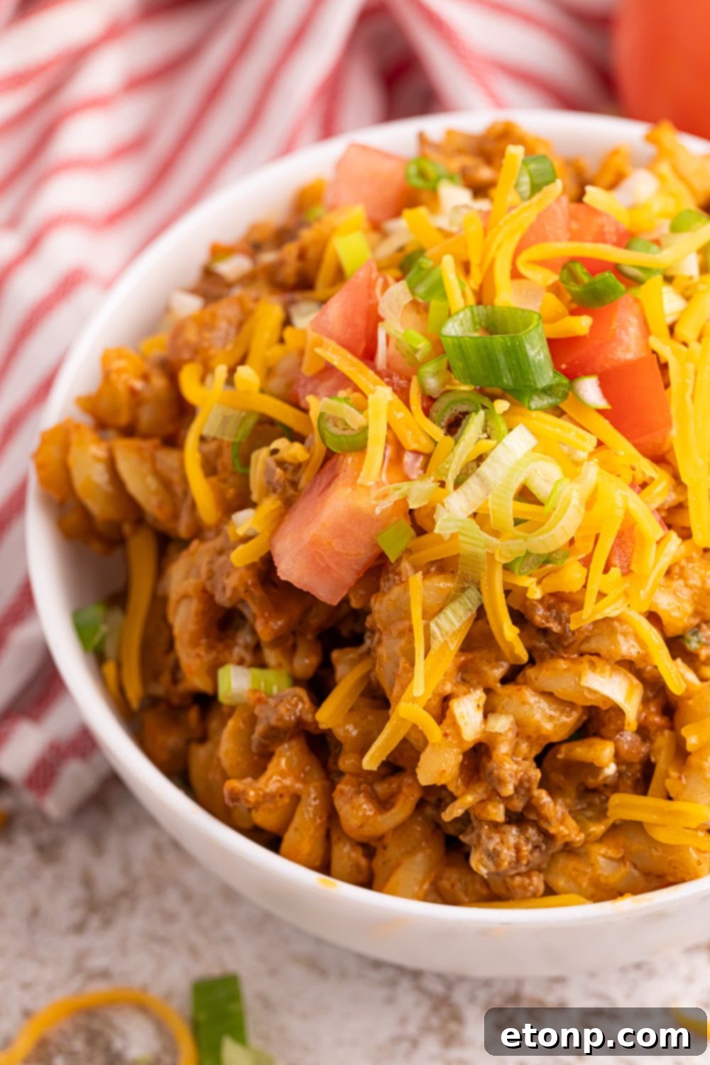 Taco Macaroni and Cheese in a bowl with cheese and tomatoes 