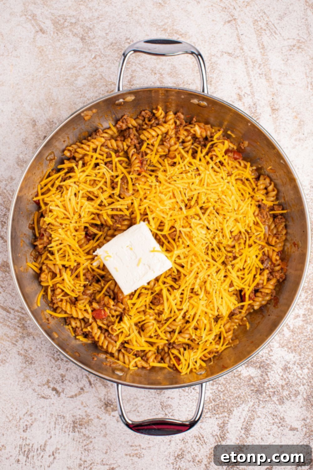 Taco Macaroni and Cheese in a skillet with cheese and cream cheese on top 
