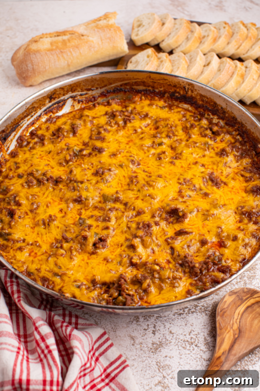 Ultimate Sloppy Joe Dip 2 A warm pan of Sloppy Joe Dip, rich with ground beef and melted cheese, surrounded by slices of toasted bread, ready for serving at a party.
