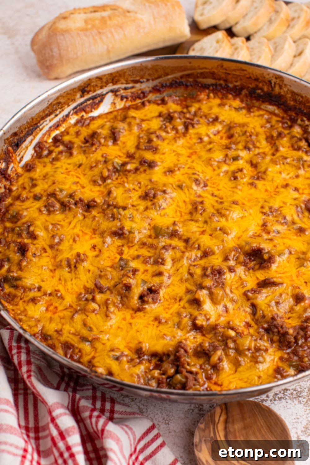 Ultimate Sloppy Joe Dip 12 A pan of rich Sloppy Joe Dip sits on a table, with a cutting board of neatly sliced bread in the soft-focused background, ready for dipping.