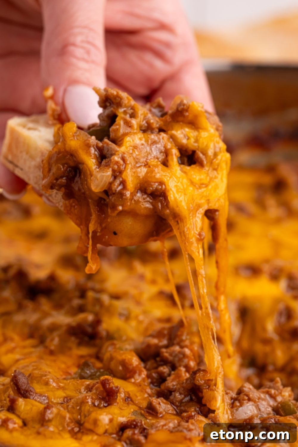 Ultimate Sloppy Joe Dip 13 A close-up shot of a piece of bread laden with a generous scoop of hot, cheesy Sloppy Joe Dip, ready to be enjoyed.
