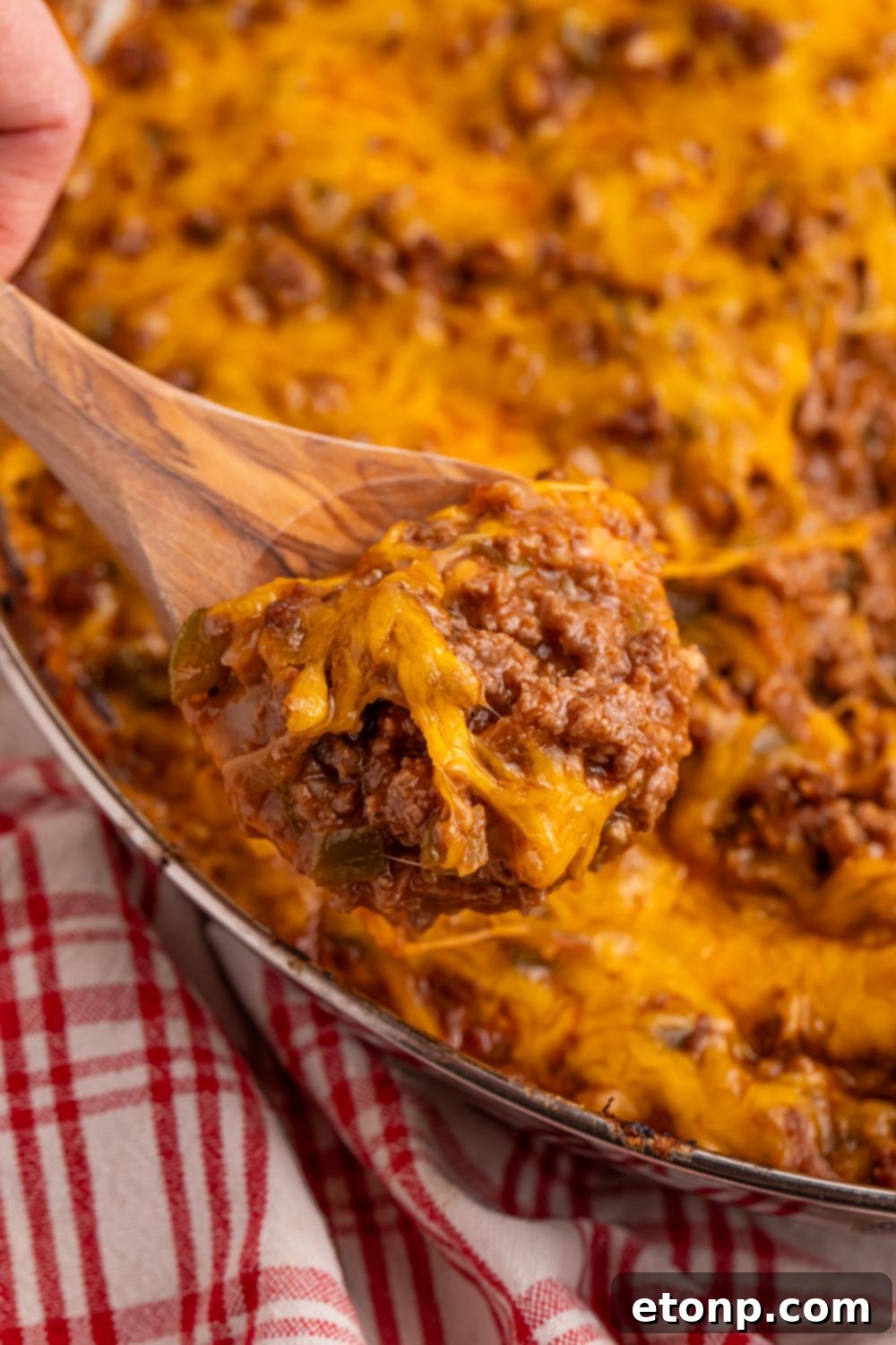 Ultimate Sloppy Joe Dip 14 A pan of savory Sloppy Joe Dip with a wooden spoon resting on its rim, glistening with rich sauce and ready to be served.