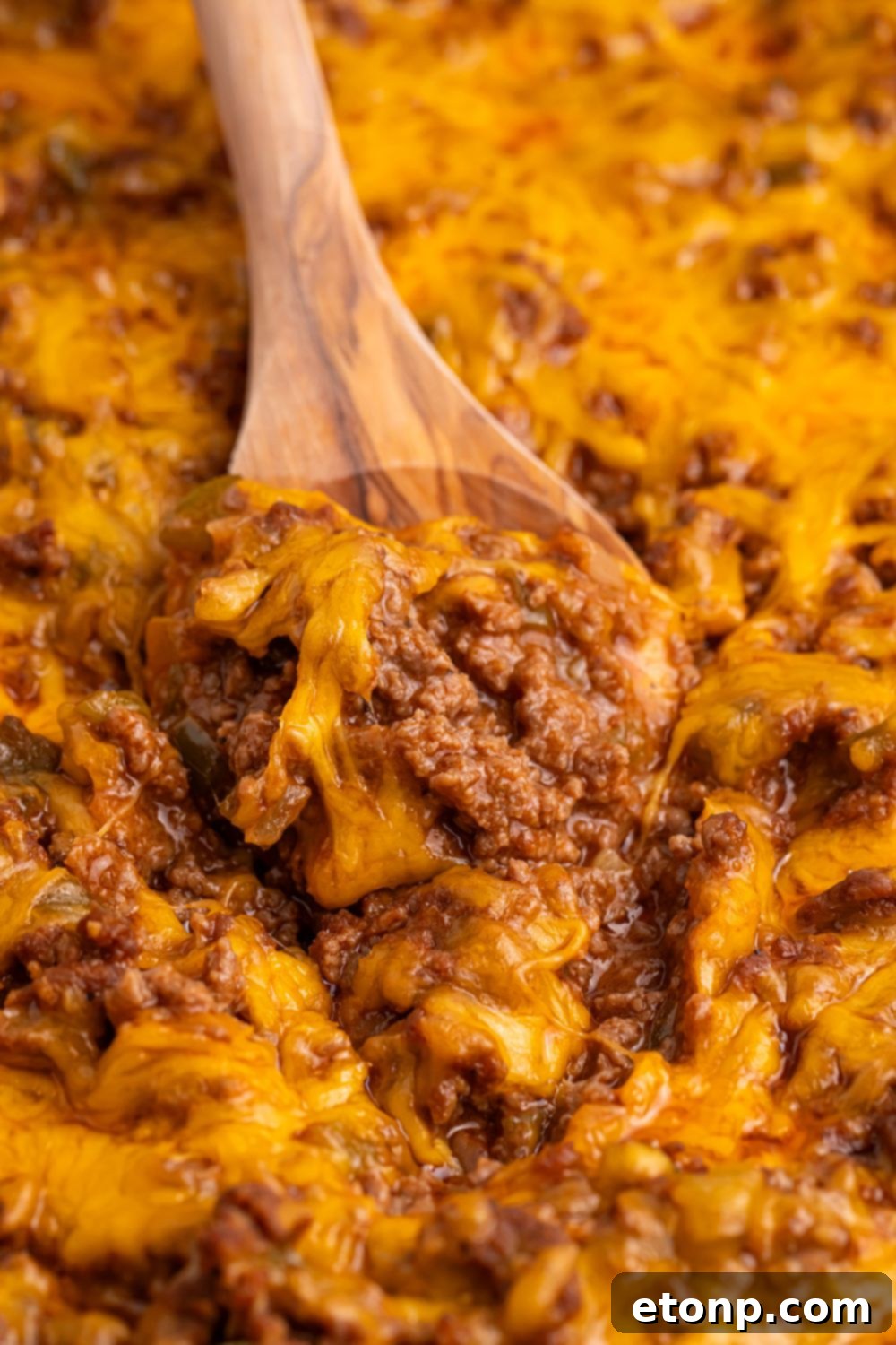 Ultimate Sloppy Joe Dip 16 A spoon laden with a hearty scoop of Sloppy Joe Dip, rich with ground beef and sauce, poised above the pan.