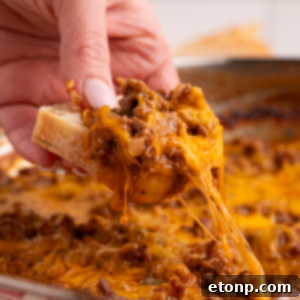 Sloppy Joe Dip in pan with a piece of bread and dip being lifted out of pan with hand