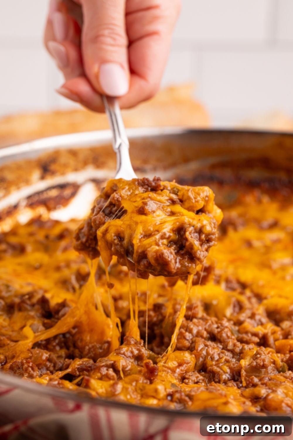 Ultimate Sloppy Joe Dip 4 A wooden spoon carefully lifts a scoop of the rich, savory Sloppy Joe Dip from a pan, highlighting its appealing consistency.